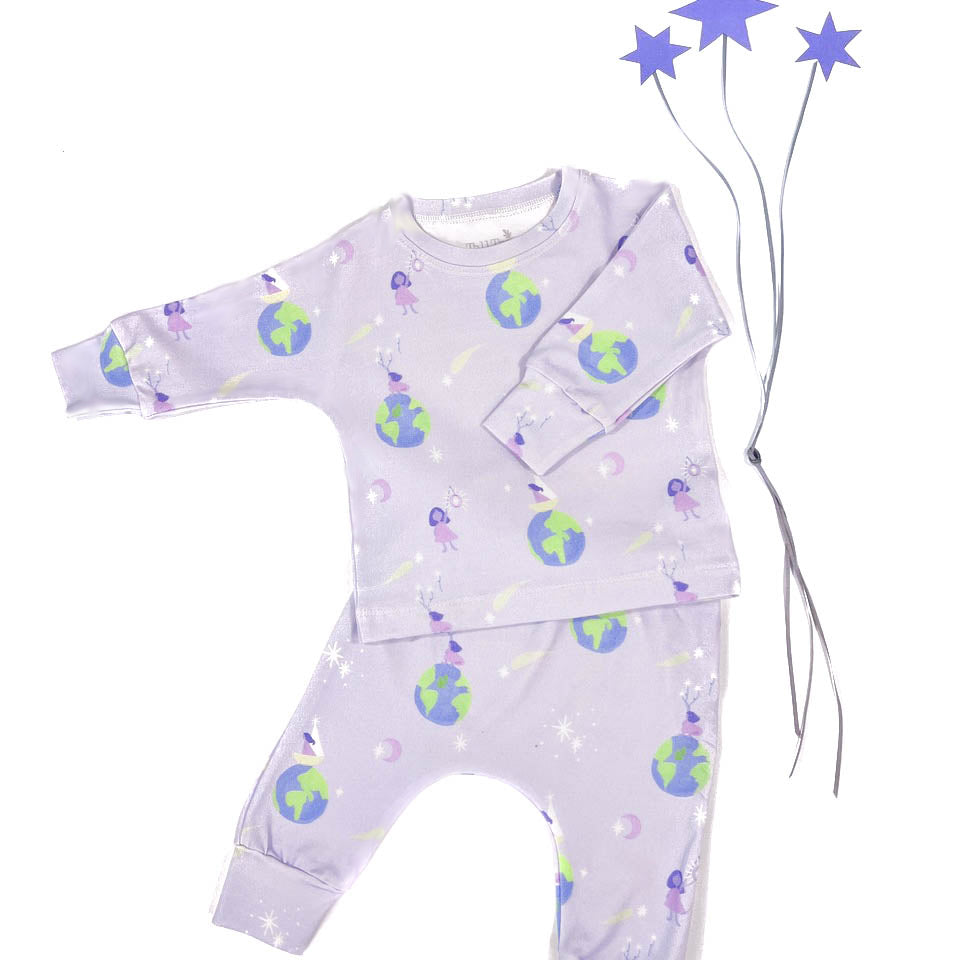 A playset for girls including a purple long-sleeved top and bottom with a pattern of a girl standing on top of the world reaching for stars, and three paper purple star accessories on a white background.